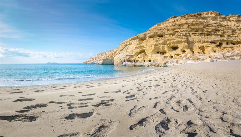 Strand van Matala omringd door grotten uitgehouwen in rotsen, Kreta